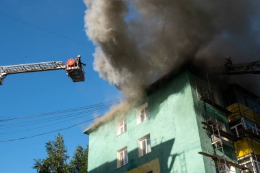 Bir konutun çatısı yanıyor. merdivenli itfaiyeciler bir konut yüksek katlı binanın çatısında bir yangın söndürmek