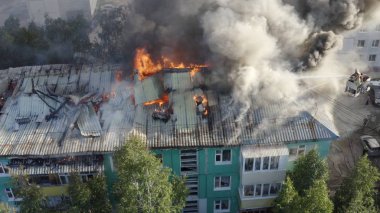 Bir konutun çatısı yanıyor. İtfaiyeciler bir konut yüksek katlı binanın çatısında bir yangın söndürmek.