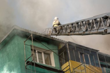 Nizhnevartovsk, Rusya - 1 Temmuz 2019: Bir konutun çatısı yanıyor. İtfaiyeciler bir konut yüksek katlı binanın çatısında bir yangın söndürmek.