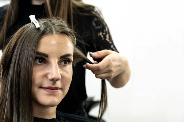 Cabeleireiro faz laminação de cabelo em um salão de beleza para uma menina com cabelo morena — Fotografia de Stock