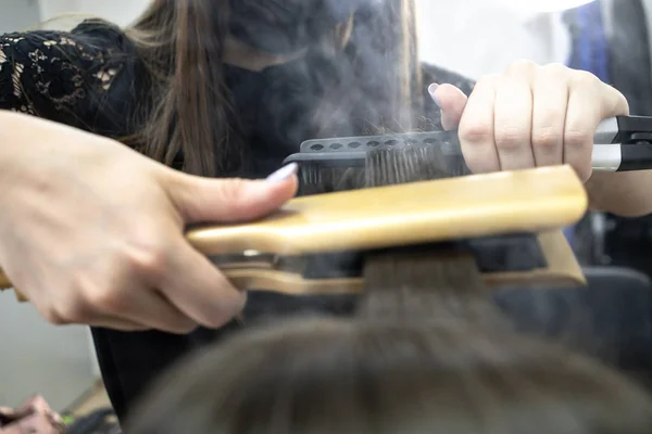 Parrucchiere fa laminazione dei capelli in un salone di bellezza per una ragazza con i capelli castani — Foto Stock