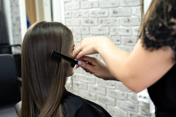 Cabeleireiro faz laminação de cabelo em um salão de beleza para uma menina com cabelo morena — Fotografia de Stock