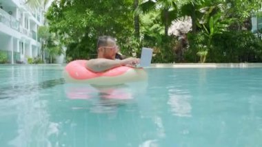 Pembe şişme daire içinde Şişman komik adam şaşırttı ve havuzda suya dizüstü düşer.