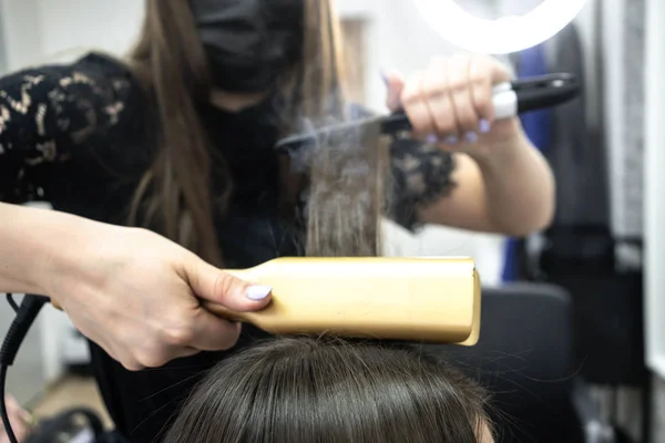 Peluquería hace laminación de cabello en un salón de belleza para una chica con pelo morena —  Fotos de Stock