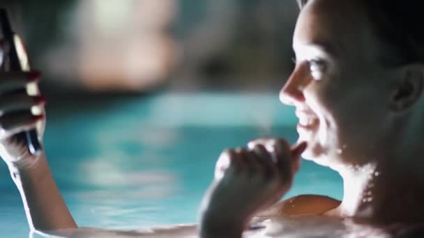 La chica en la piscina, por la noche con el teléfono, el concepto de vacaciones de los negocios — Vídeos de Stock