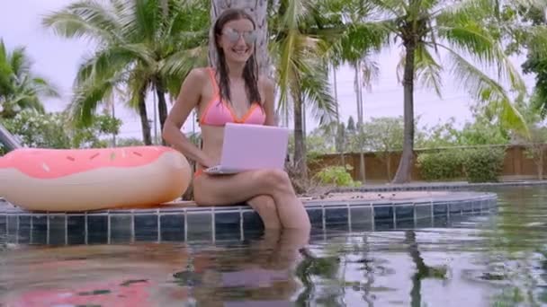 A young woman sits by the pool with minicomputer. selective focus — Stock Video