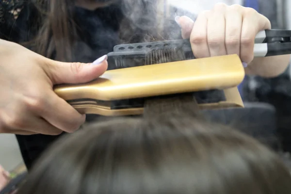 Friseur macht Haarlaminierung in einem Schönheitssalon für ein Mädchen mit brünetten Haaren — Stockfoto