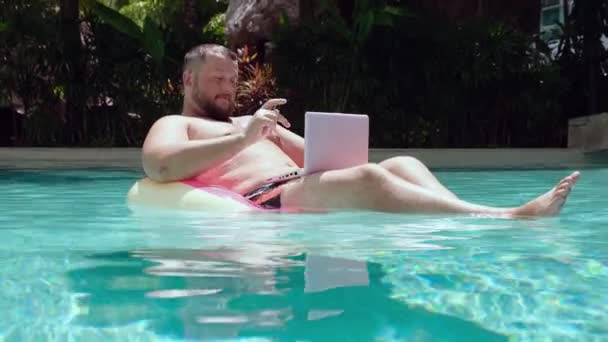 Male businessman with a laptop on rubber ring in the water — Stock Video