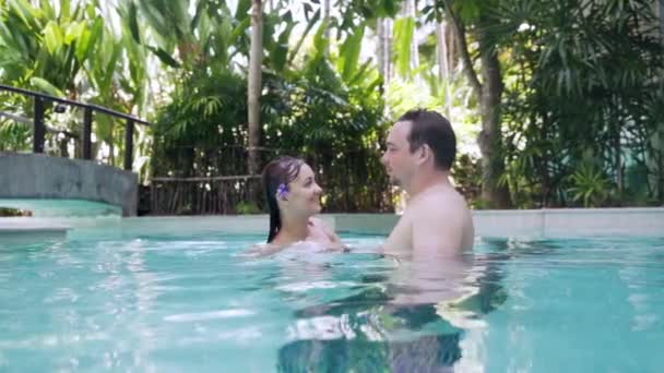 Joven hombre y mujer en la piscina feliz sonriendo, él la da la vuelta . — Vídeo de stock