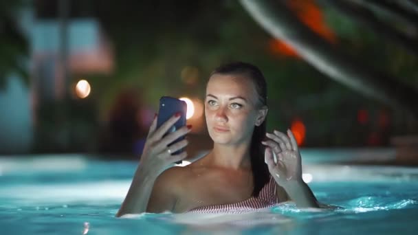 Havuzda kız, gece telefon ile, iş tatil kavramı — Stok video