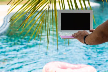 Havuz kenarında otururken bir adam onun laptop yazarak. Havuzda klavyede Mens eller