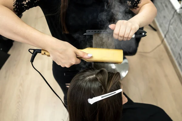 Peluquería hace laminación de cabello en un salón de belleza para una chica con pelo morena —  Fotos de Stock