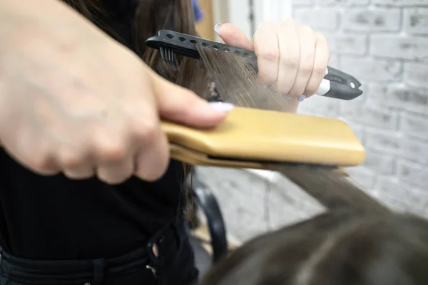 美容師は、ブルネットの髪を持つ女の子のための美容院でヘアラミネートを行います — ストック写真