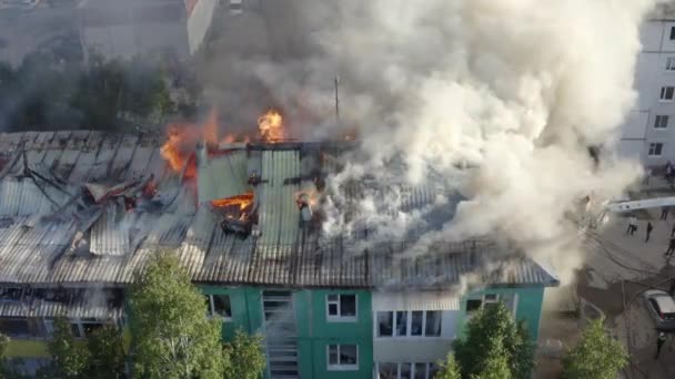 Η στέγη ενός οικιστικού σπιτιού καίγεται. πυροσβέστες σβήνουν μια φωτιά στην οροφή ενός οικιστικού κτηρίου υψηλής ανόδου. — Αρχείο Βίντεο