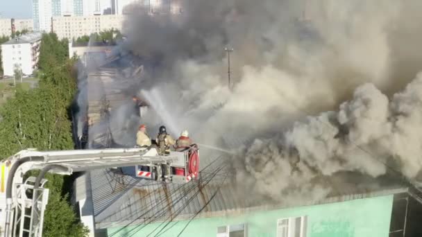 Nizhnevartovsk, Ryssland-1 juli 2019: brandmän släcka en brand på taket av ett bostadshus höghus — Stockvideo