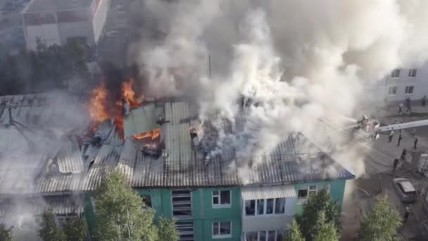 Het dak van een woonhuis brandt. Brandweerlieden blussen een brand op het dak van een residentiële hoogbouw. — Stockvideo