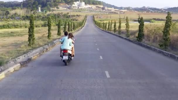 Ένα ζευγάρι βόλτες το καλοκαίρι με ένα ποδήλατο σε ένα όμορφο δρόμο, εναέρια θέα — Αρχείο Βίντεο