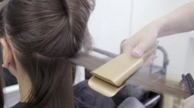 Kuaför esmer saçlı bir kız için bir güzellik salonunda saç laminasyon yapar
