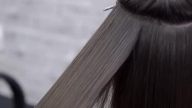 Kuaför esmer saçlı bir kız için bir güzellik salonunda saç laminasyon yapar
