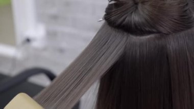 Kuaför esmer saçlı bir kız için bir güzellik salonunda saç laminasyon yapar
