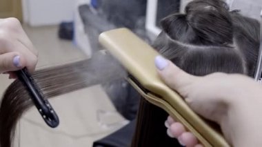 Kuaför esmer saçlı bir kız için bir güzellik salonunda saç laminasyon yapar