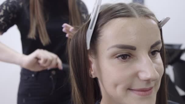 Cabeleireiro faz laminação de cabelo em um salão de beleza para uma menina com cabelo morena — Vídeo de Stock