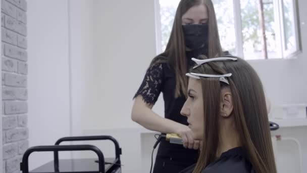 Cabeleireiro faz laminação de cabelo em um salão de beleza para uma menina com cabelo morena — Vídeo de Stock