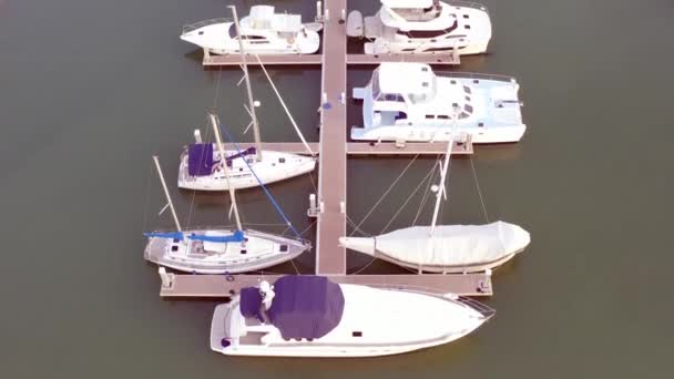 游艇俱乐部和码头的无人机鸟瞰图。游艇俱乐部的顶景。海水中的白船。码头游艇和小摩托。游艇和帆船 — 图库视频影像