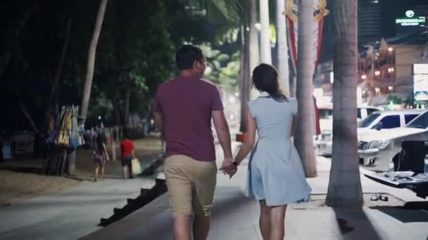 Una joven pareja va de la mano por la ciudad nocturna. De cerca. — Vídeo de stock