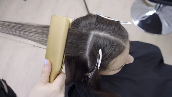 Parrucchiere fa laminazione dei capelli in un salone di bellezza per una ragazza con i capelli castani — Foto Stock