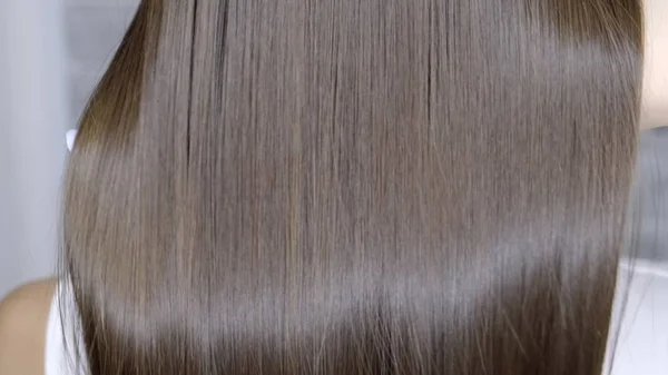 Αποτέλεσμα μετά από πλαστικοποίηση και ίσιωμα των μαλλιών σε ένα σαλόνι ομορφιάς για ένα κορίτσι με καστανά μαλλιά. έννοια της φροντίδας των μαλλιών — Φωτογραφία Αρχείου