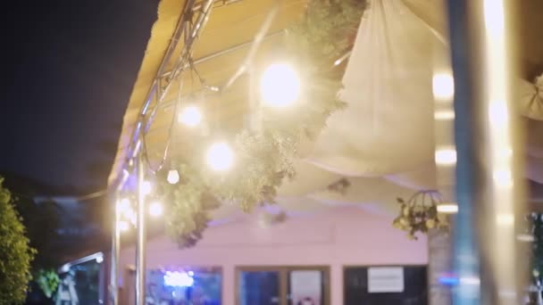 Outdoor garland lights bokeh. Outdoor white garland lights on roof. — Stock Video