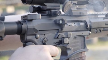 Bir adam modern bir tüfeği vurur. Yakın çekim