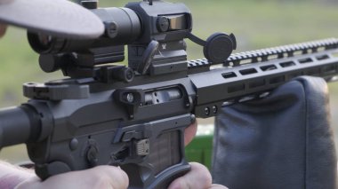 Bir adam modern bir tüfeği vurur. Yakın çekim