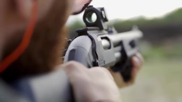 Moedige man met een baard in glazen, schiet van een shotgun in de open lucht. Close-up, slow mo. — Stockvideo