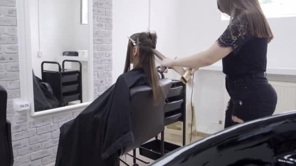 Coafeză face laminarea părului într-un salon de înfrumusețare pentru o fată cu păr brunet — Videoclip de stoc
