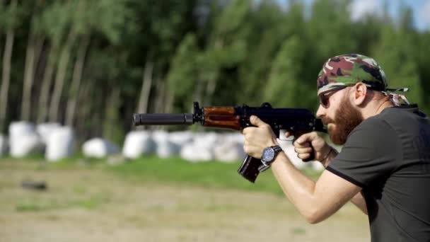 Hombre valiente con barba en gafas, dispara desde un rifle al aire libre. Primer plano, lento mo . — Vídeos de Stock