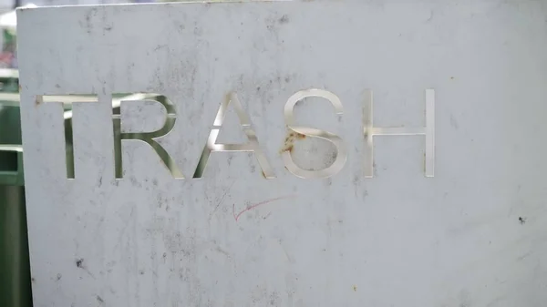 Napis tresh na żelaznej powierzchni metalowej. W pobliżu zielonych pojemników na śmieci — Zdjęcie stockowe