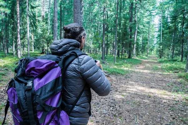 En man med en stor turist ryggsäck som färdas genom skogen, ekoturism konceptet. — Stockfoto
