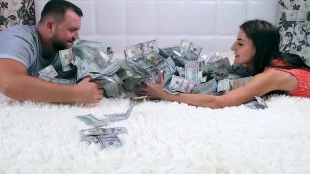 Ένας άντρας και μια γυναίκα μοιράζονται χρήματα καθισμένος σε ένα λευκό κρεβάτι, διασκεδάζουν βιαστικά και τα θεωρούν. Θέα από πάνω. Πολλά λεφτά. Σχέδιο γρήγορου χρήματος — Αρχείο Βίντεο