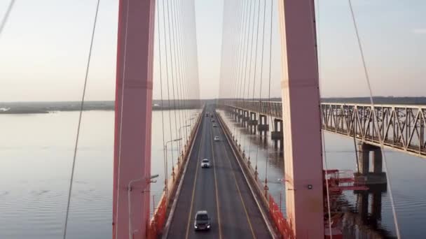 Flyg flyga över och genom en kabel-stannade bro stående ovanför floden i solnedgången. 4K — Stockvideo