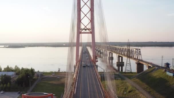 Vuele aéreo por encima y a través de un puente con cable sobre el río bajo el sol poniente. 4k — Vídeo de stock