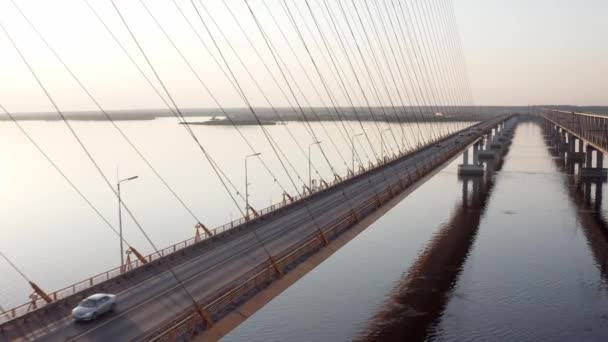 Vuele aéreo por encima y a través de un puente con cable sobre el río bajo el sol poniente. 4k — Vídeo de stock