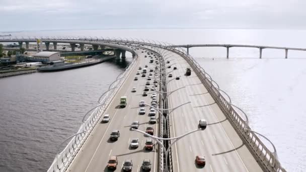 Un vol aérien en douceur, un vol au-dessus d'un pont au-dessus d'une rivière sur laquelle les voitures roulent. 4k . — Video
