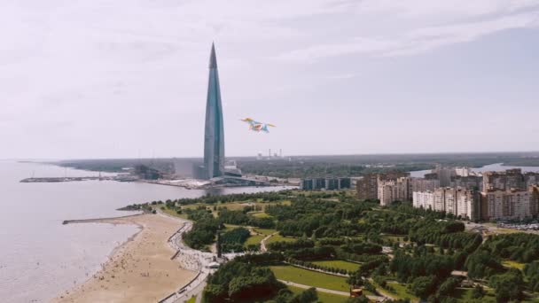 Een Kite vliegen in de buurt van de rivieroever, naast een prachtig hoog gebouw. Concept van vrijheid en succes — Stockvideo