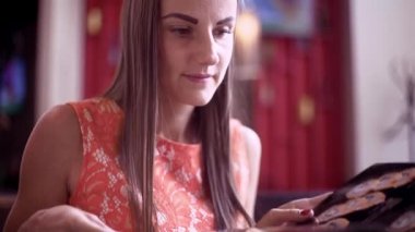 Kafede bir kadın, bir smoothie içiyor, menüde yapraklar, telefondaki mesajları okuyor ve cevabı yazıyor. Yakın çekim