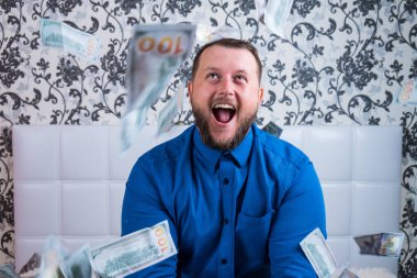 Mavi gömlekli sakallı iyi bir adam, dolarlara sevinir, onları kusar ve sayar. Piyango kazanın