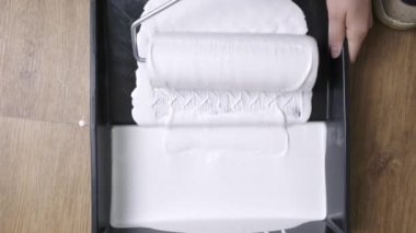 Odayı beyaz boyaile boyamak, beyaz boya ile boyamak için bir rulo daldırma.