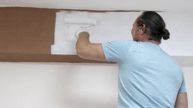 Odayı beyaz boyaile boyamak, beyaz boya ile boyamak için bir rulo daldırma.