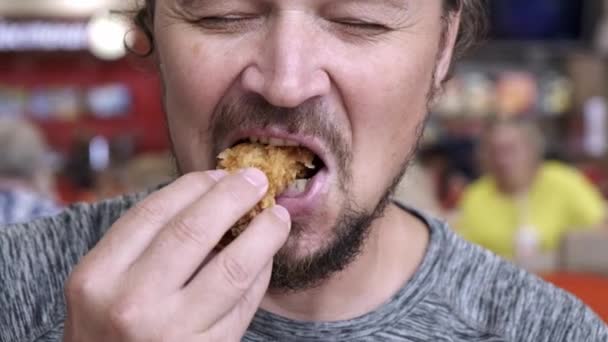 Hombre adulto comiendo comida rápida y sonriendo, de cerca — Vídeos de Stock